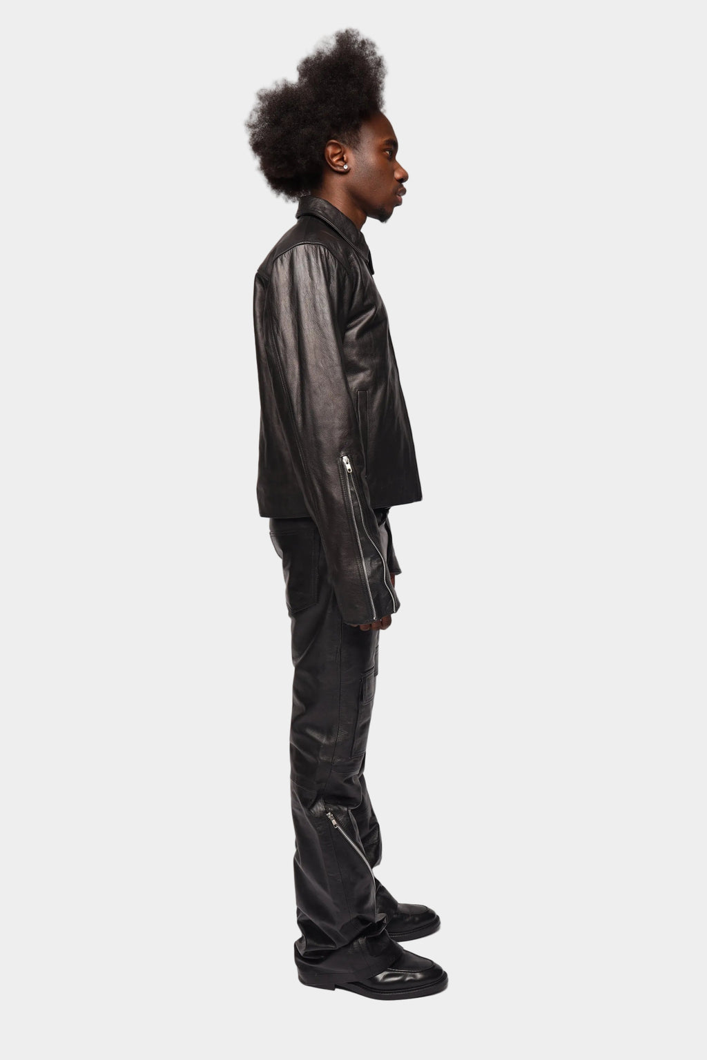 Black zipped leather cargo pants by Kaleb A. Bearden with multiple pockets and a slim fit design.
