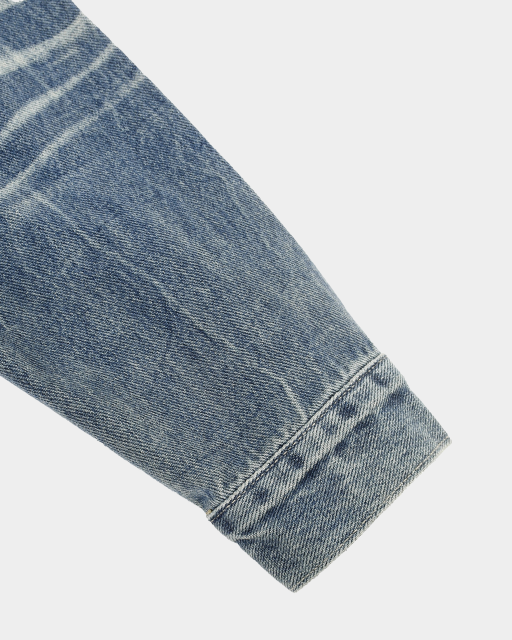 Kaleb A. Bearden washed denim jacket displayed on a hanger, showcasing the light, faded blue denim with classic collar and button details.