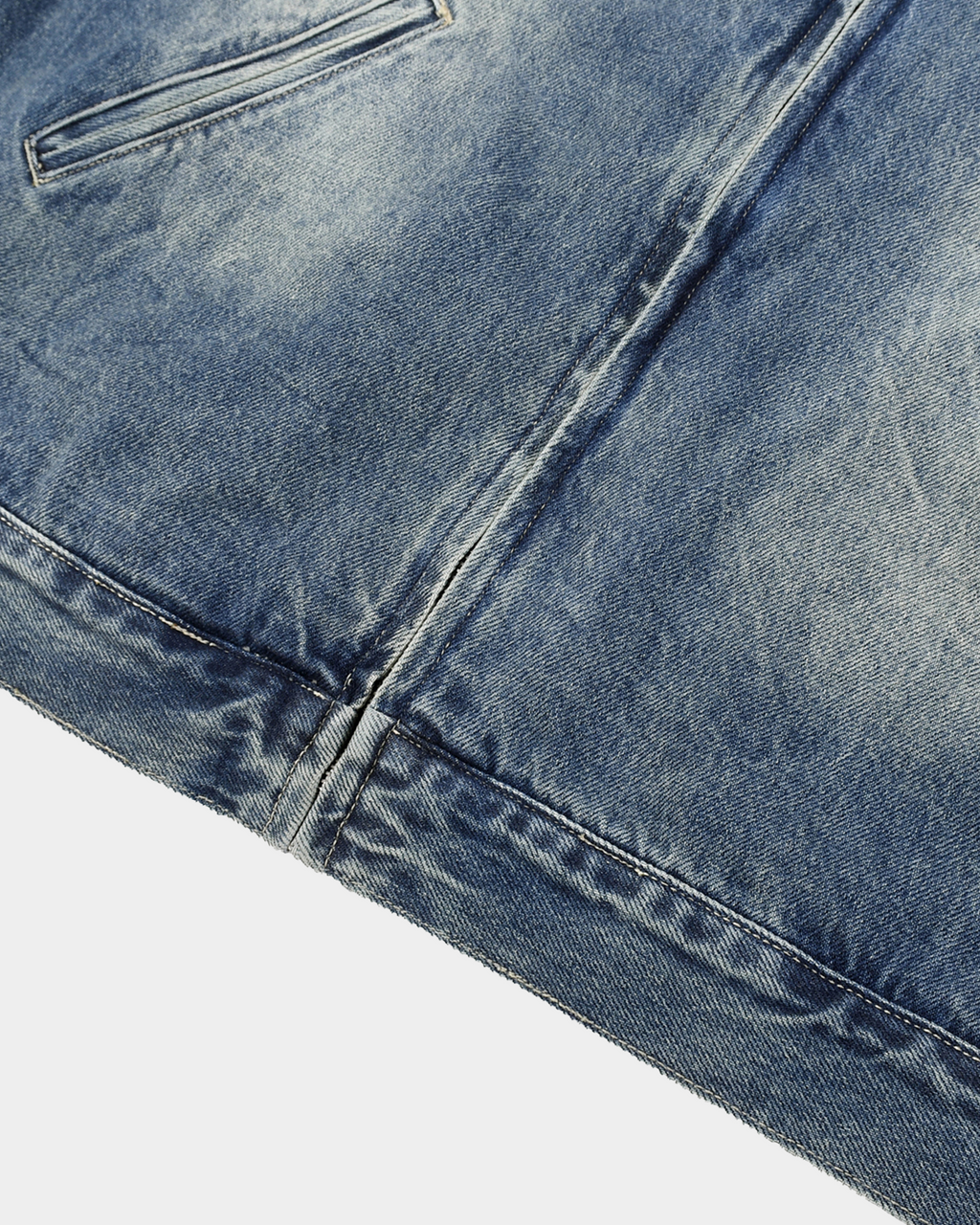 Washed denim jacket by Kaleb A. Bearden hanging on a hanger, showcasing its classic blue color and casual style.